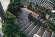 Explore the elegance of a wooden staircase surrounded by lush greenery in an outdoor garden.